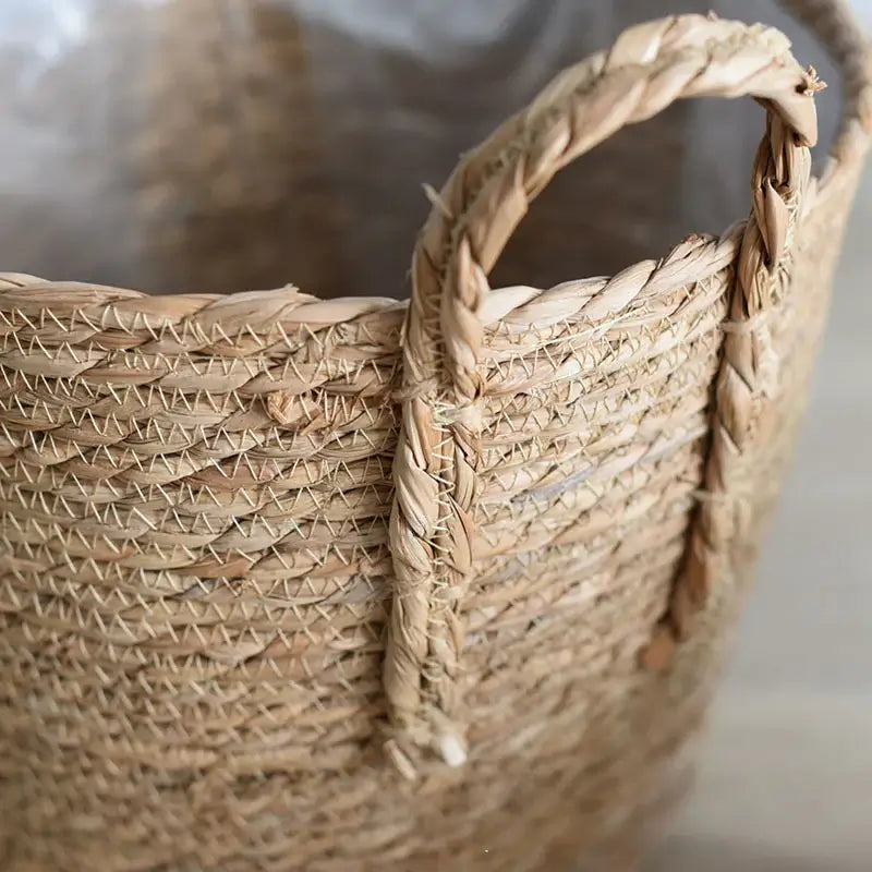 Close-up of Nordic handmade straw woven flower pot with sturdy handles, showcasing intricate plant fiber weaving.