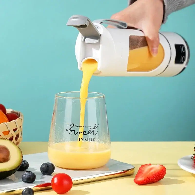 Mini portable electric juicer pouring fresh orange juice into a glass, surrounded by fruits like avocados, berries, and strawberries.